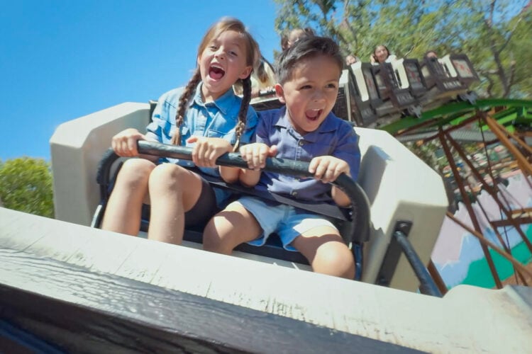 Two young children ride a kids' coaster at Six Flags Magic Mountain