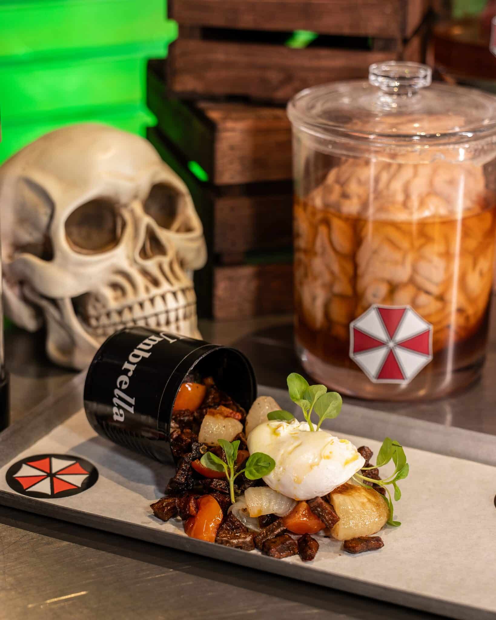 A poached-egg hash spills from an Umbrella Corporation can beside a brain specimen jar at Universal Horror Unleashed.