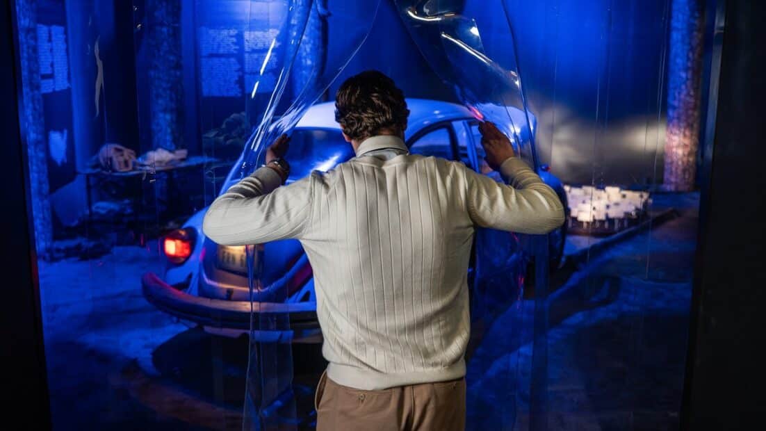 A visitor enters a blue-lit crime-scene recreation at The Mind of a Serial Killer exhibition